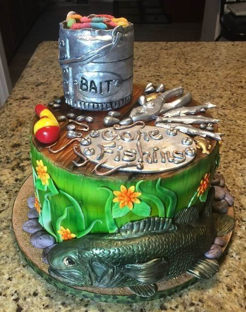 Colorful fishing-themed cake with a bait bucket, lures, worms, and a fish at the base