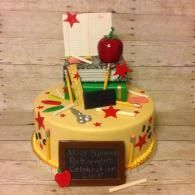 Decorated yellow cake with red apple, pencils, and star toppers on a wooden table