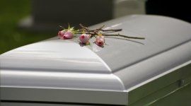 quattro rose appoggiate su un cofano funebre