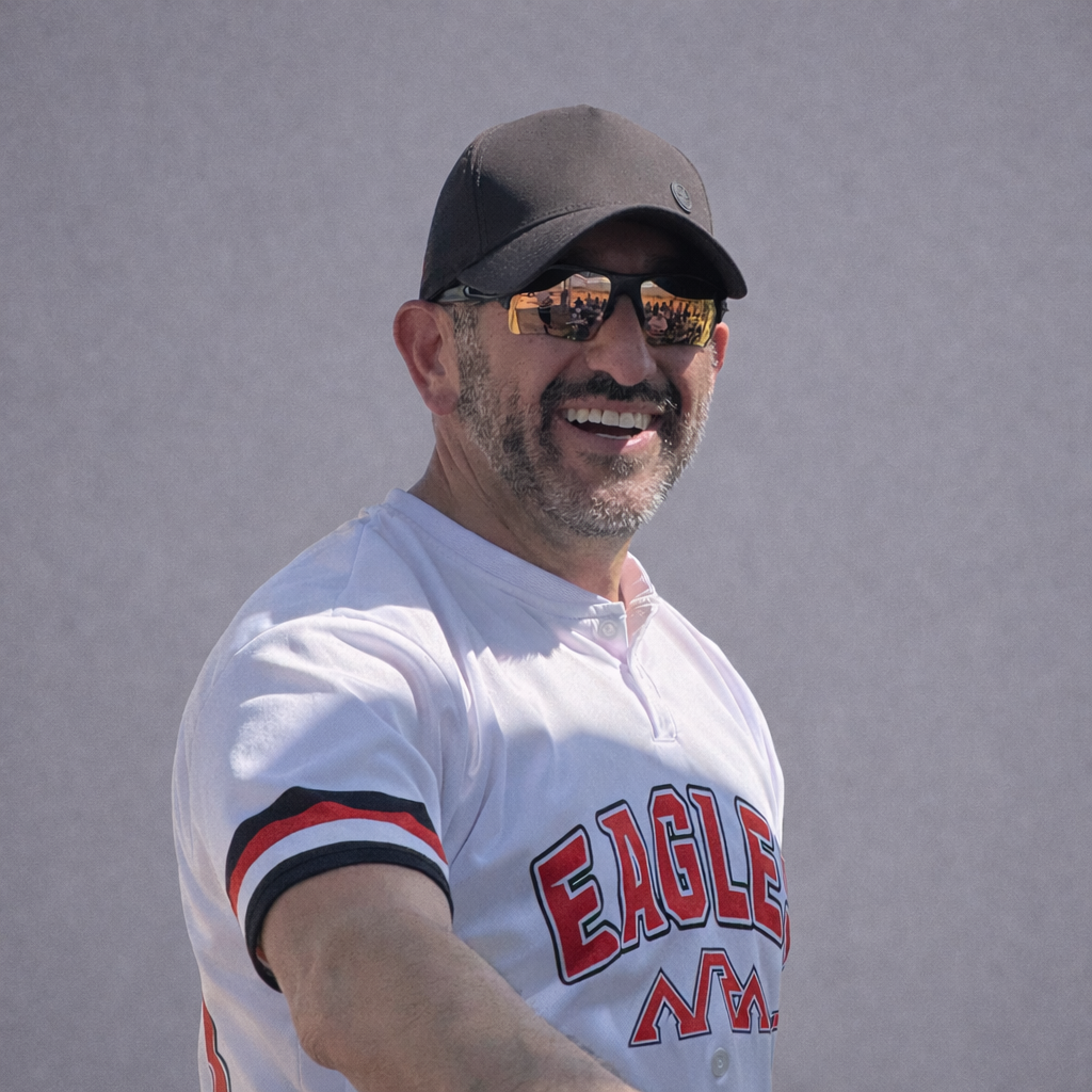 Man in sunglasses and black cap wearing a white Angels jersey, smiling outdoors against a gray background