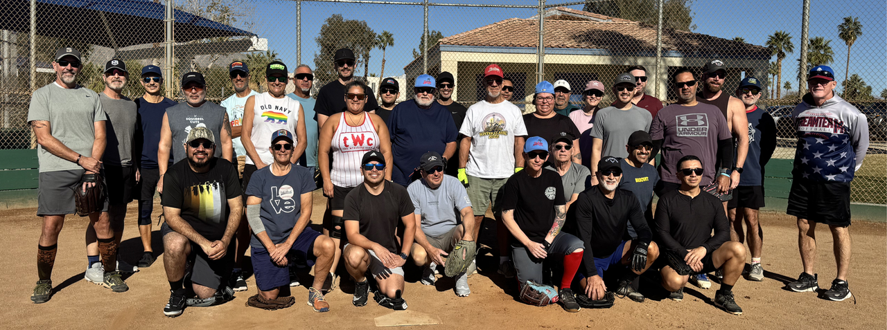 Group of people posing outdoors on a baseball field, some standing and some kneeling, with bats and gloves.