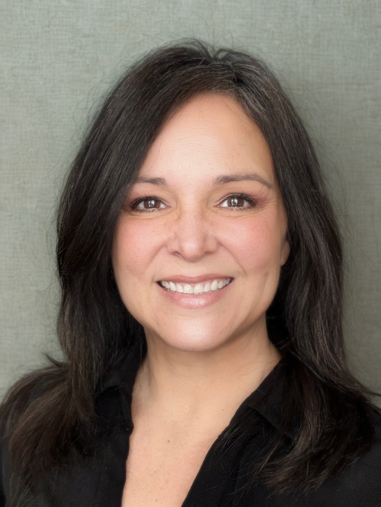 A woman with long dark hair is smiling for the camera.
