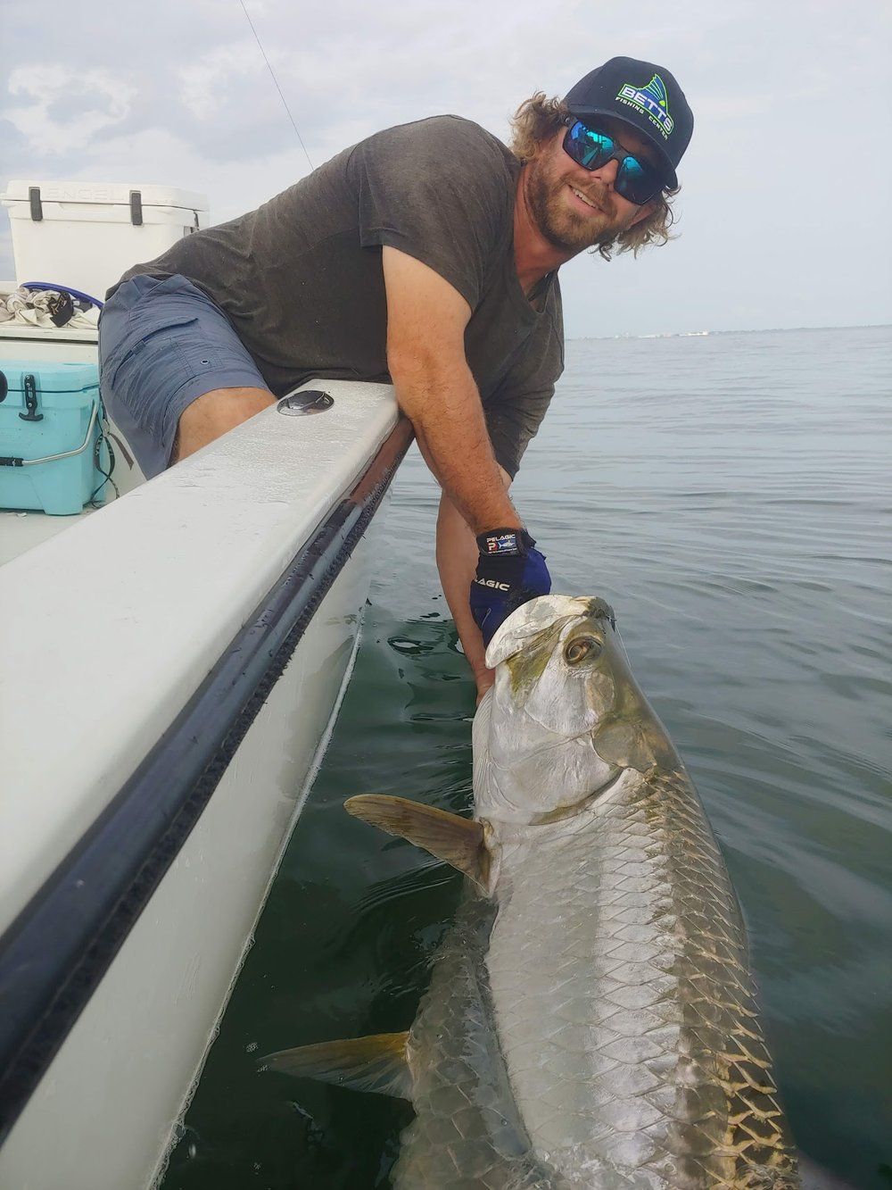 A man in a boat is holding a large fish in the water.