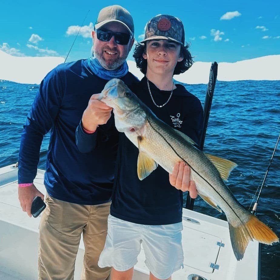 A man and a boy holding a large fish on a boat