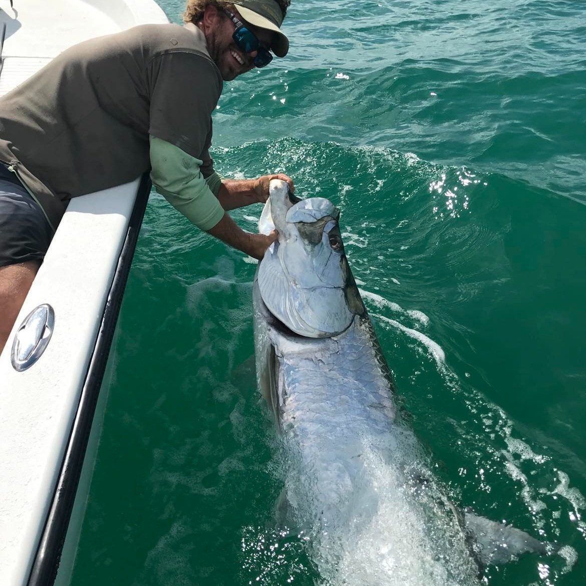 A man is holding a large fish in the water