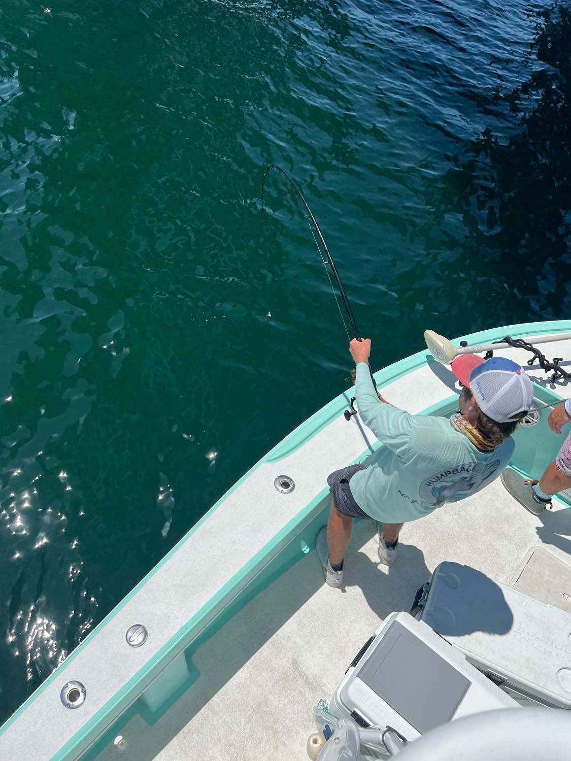 A man is fishing on a boat in the ocean