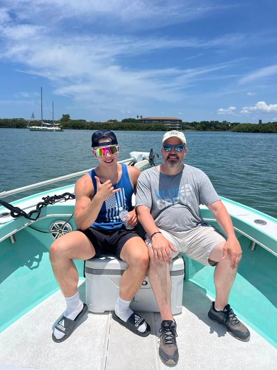 Two men are sitting on the front of a boat in the water.