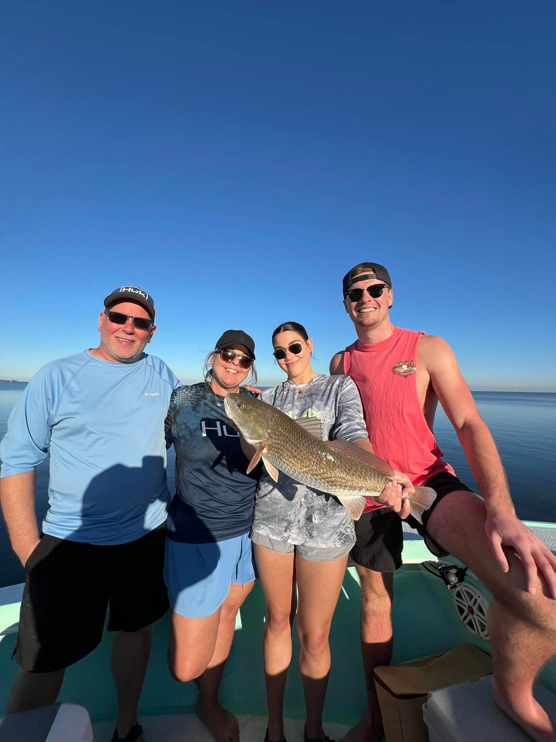 A group of people standing on a boat holding a large fish.
