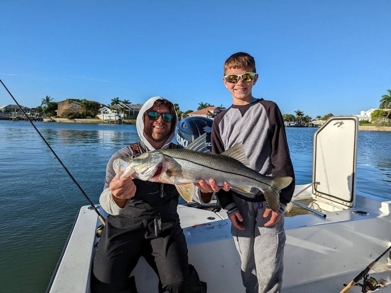 A man and a boy are holding a large fish on a boat.