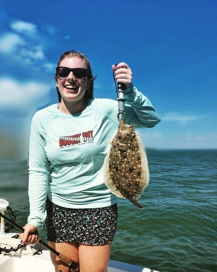 A woman is holding a fish on a boat in the ocean.