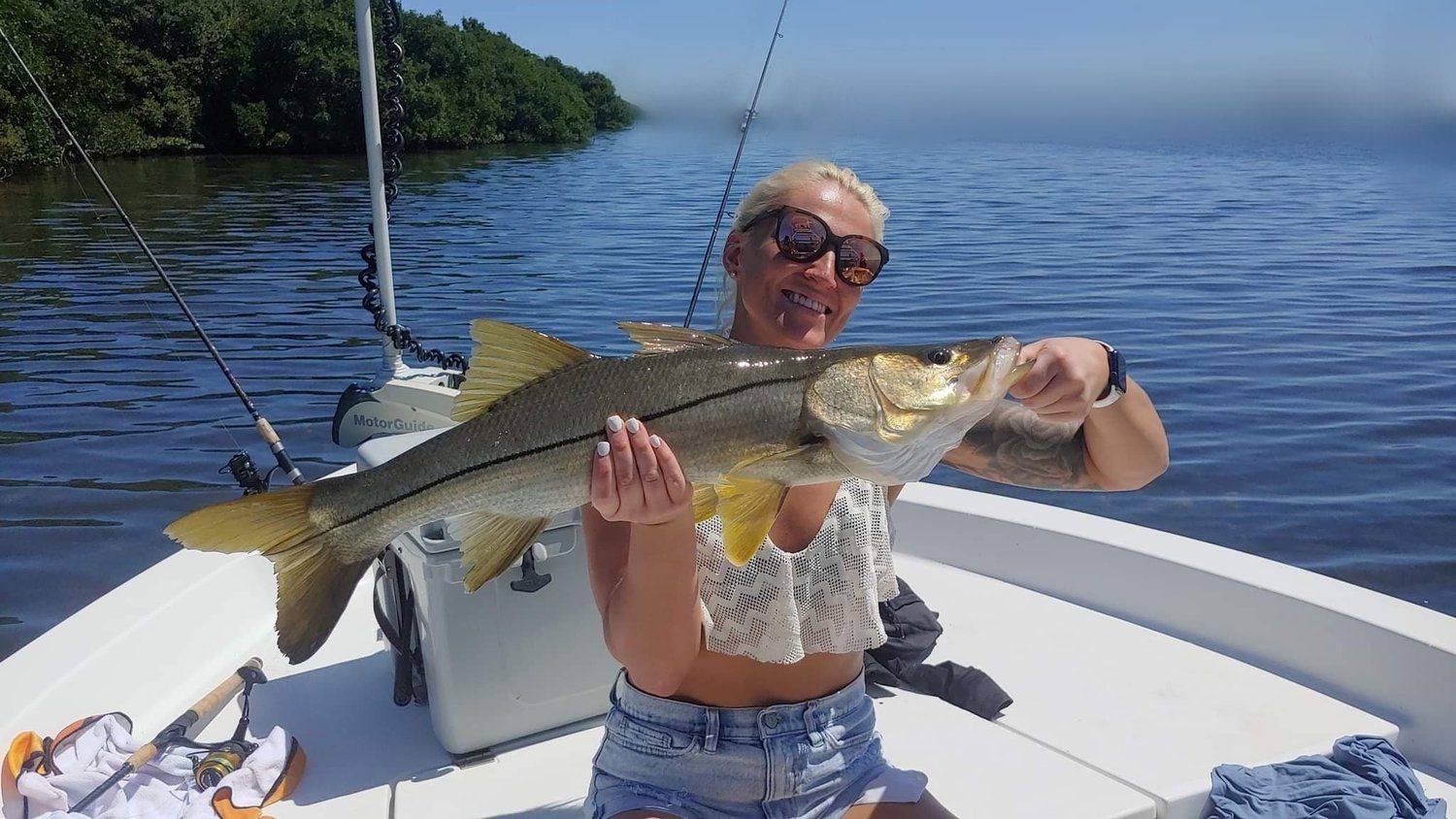 A woman is sitting on a boat holding a large fish.