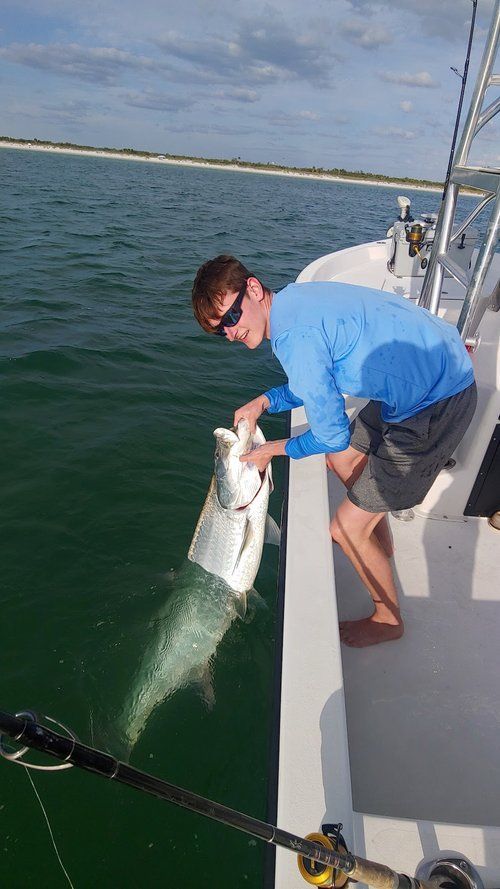 A man is holding a large fish on the side of a boat.
