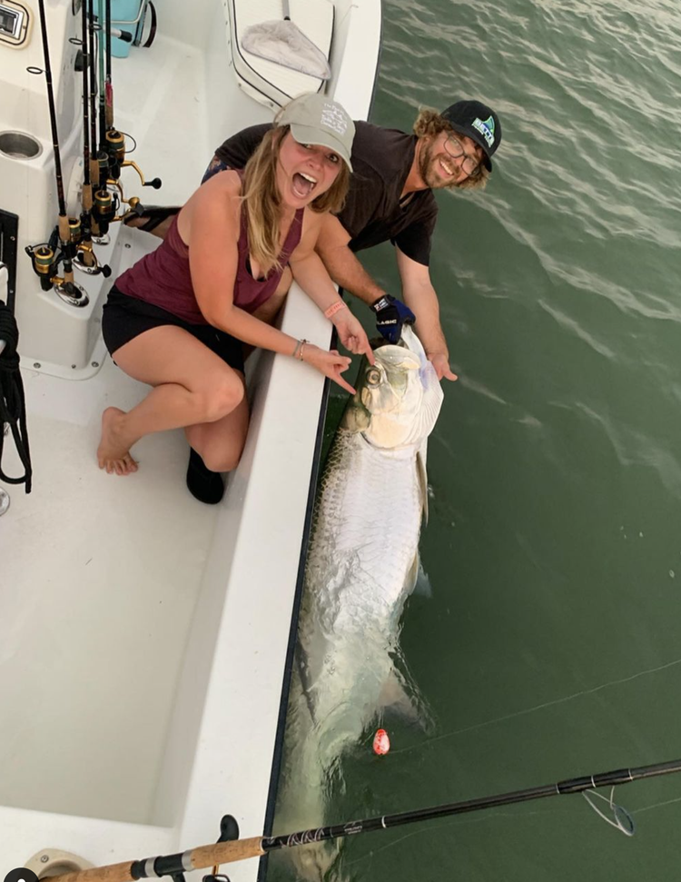 A man and a woman are holding a large fish on a boat.