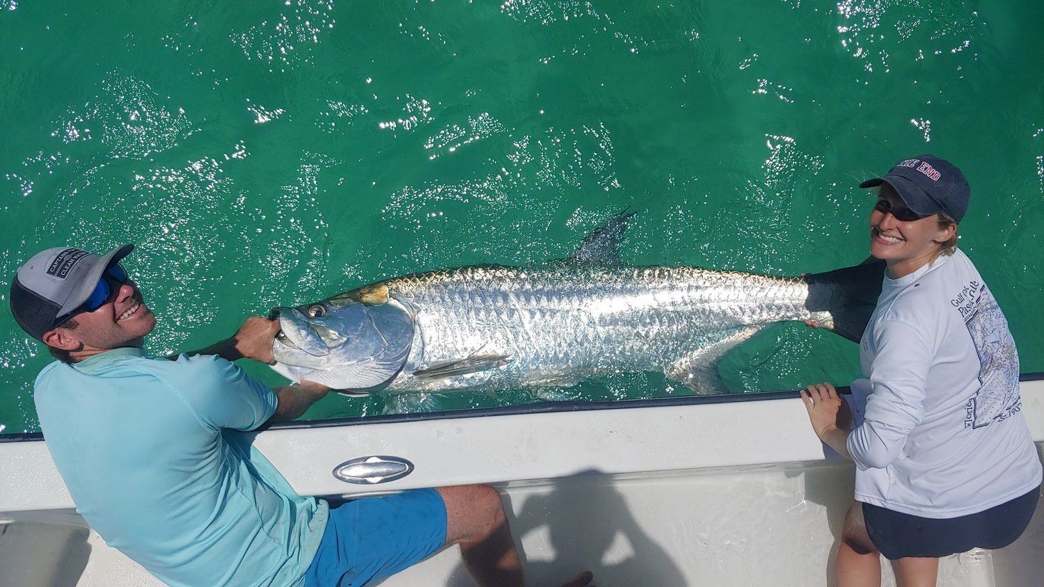 A man and a woman are holding a large fish on a boat.