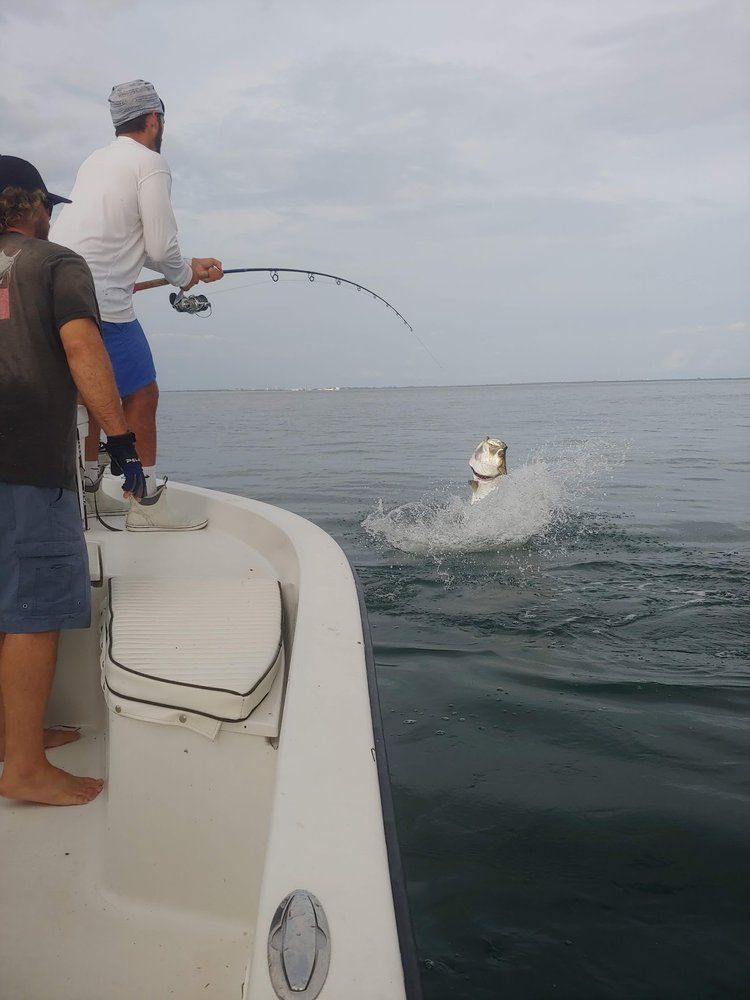 Two men are fishing in the ocean on a boat.