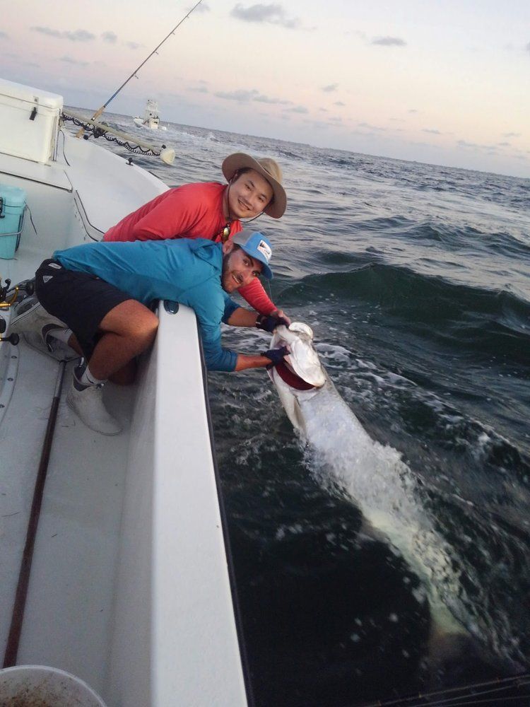 Two people are fishing in the ocean on a boat
