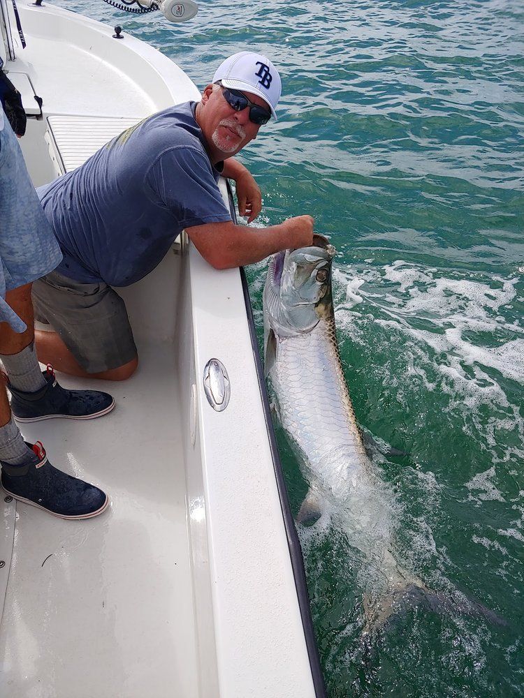 A man is kneeling on a boat with a fish in his mouth.