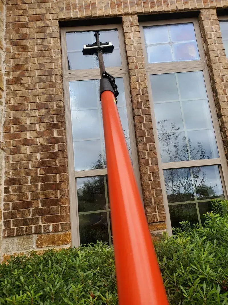 A window cleaner is cleaning the windows of a brick building.