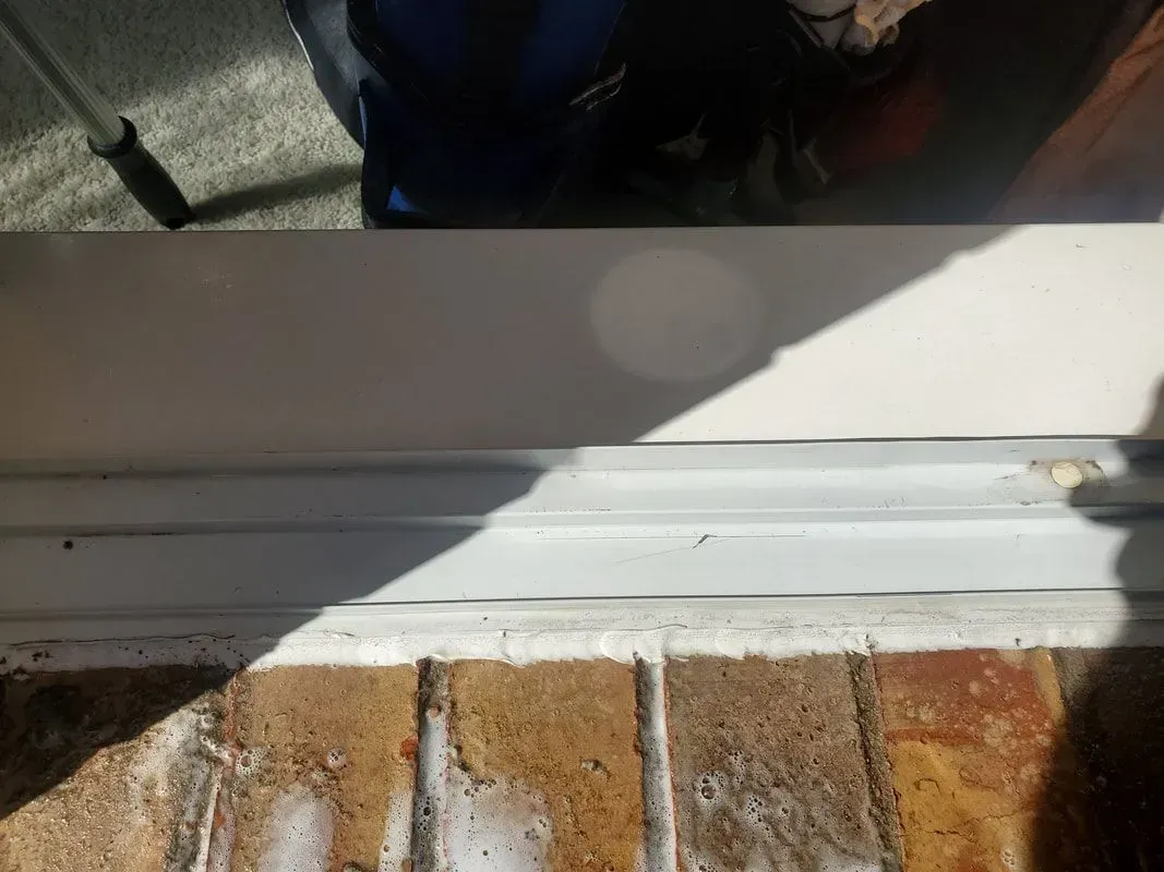 A white sliding glass door is sitting on top of a brick floor.