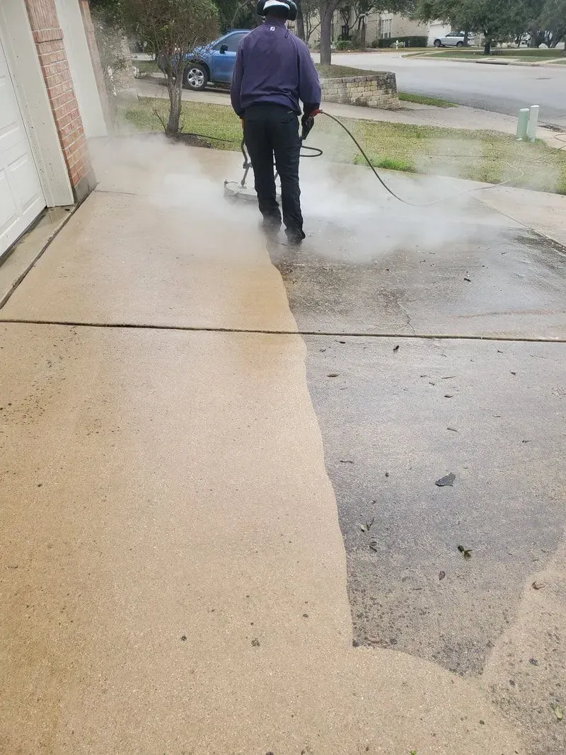 A man is cleaning a sidewalk with a pressure washer.