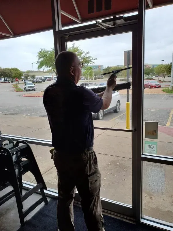 A man is cleaning a glass door with a squeegee