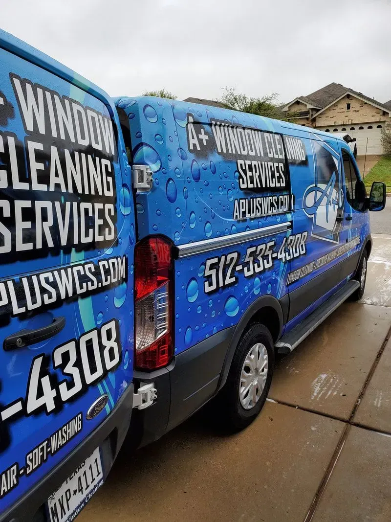Two blue vans are parked next to each other on the side of the road.