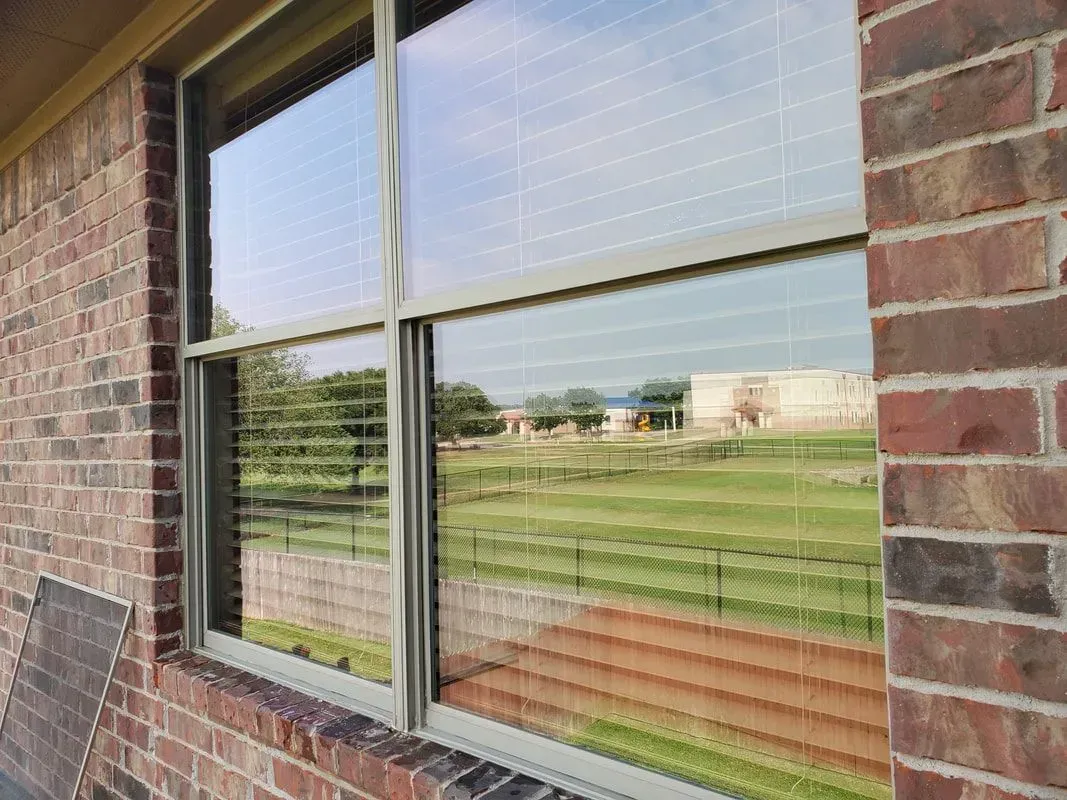 A brick building with a window with blinds on it.