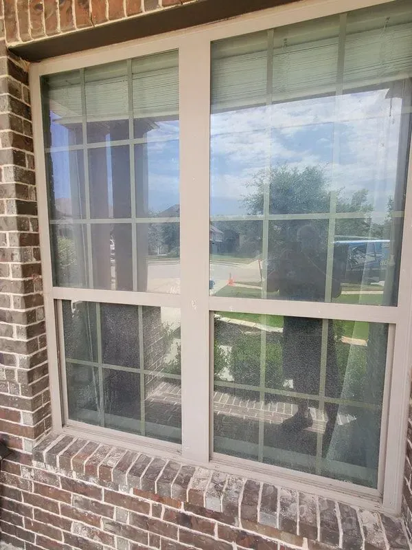A window on a brick building with a reflection of a person in the window.