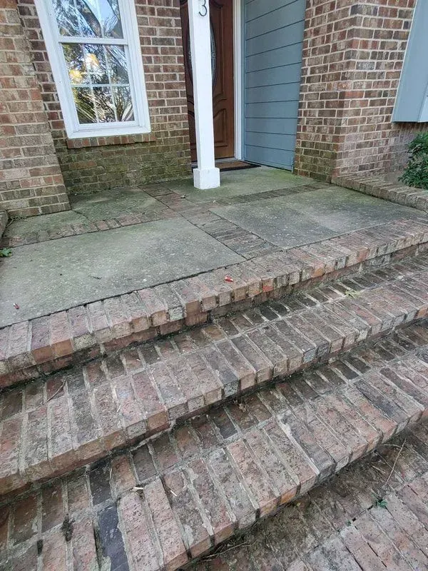 A brick porch with steps leading up to the front door of a brick house.