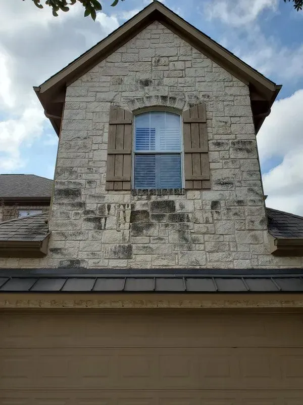 A brick building with a window and shutters on it