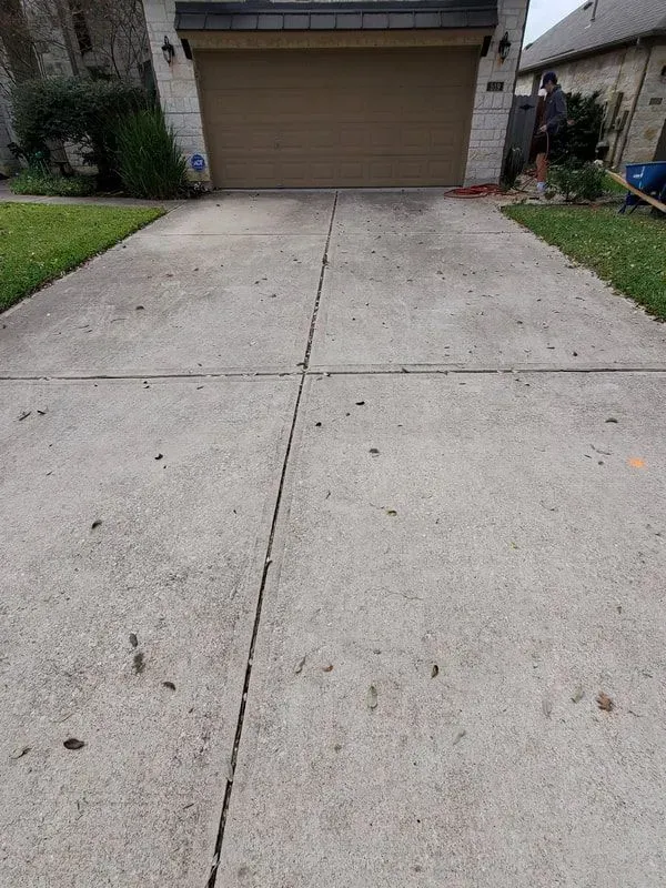 A concrete driveway with a garage door in the background.