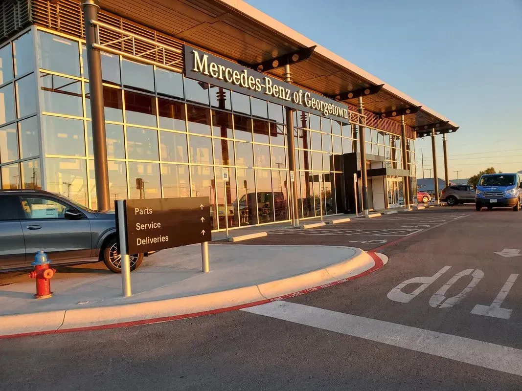 A car is parked in front of a mercedes benz dealership.