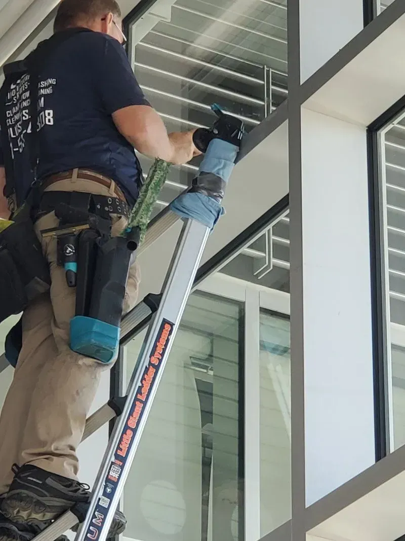 A man is standing on a ladder cleaning a window