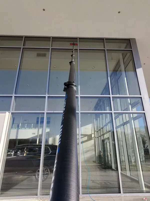 A tall pole is cleaning the windows of a building.