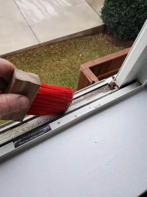 A person is cleaning a window with a red brush