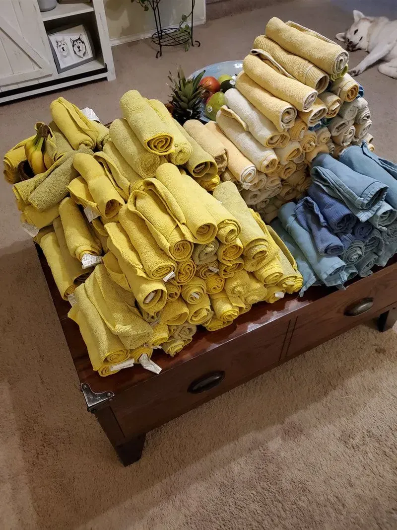 A bunch of yellow towels are stacked on top of each other on a coffee table.