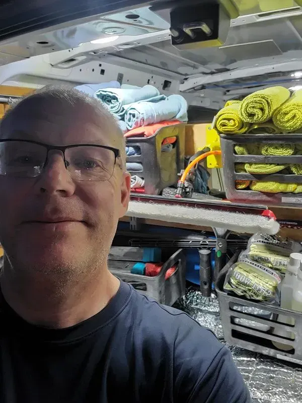A man wearing glasses is taking a selfie in the back of a van.