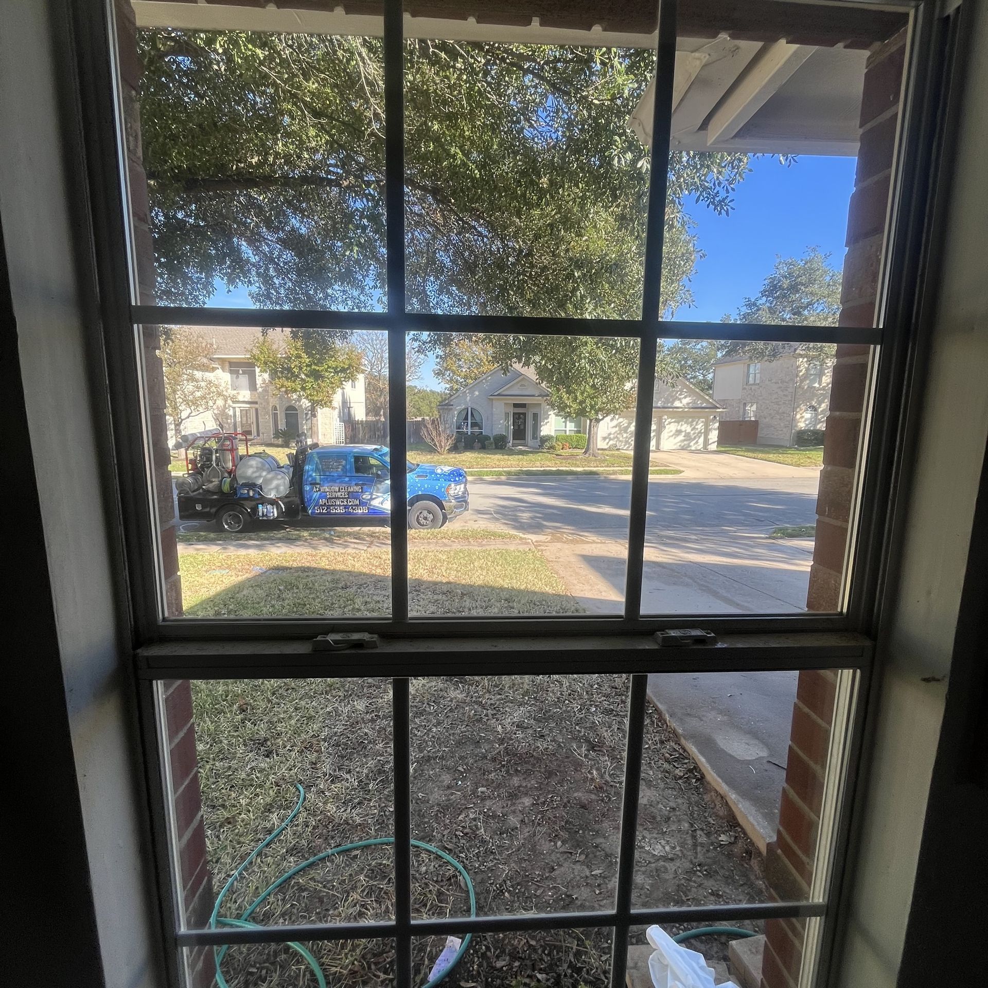 A blue truck is parked in front of a brick house.