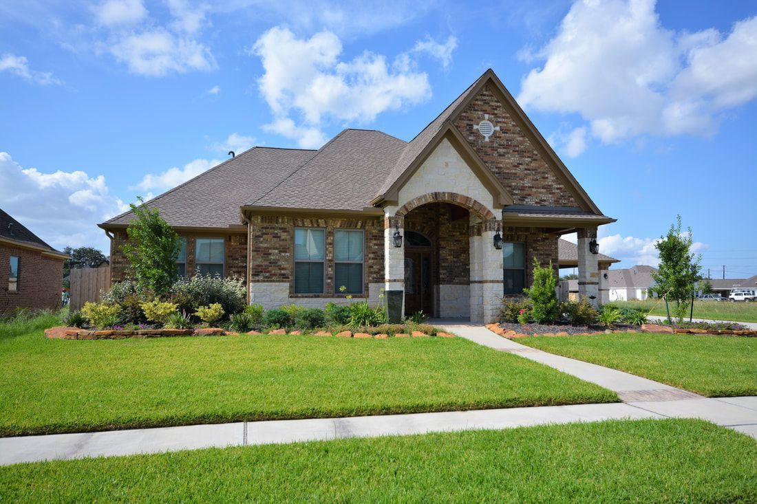 a large brick house with a lush green lawn in front of it .