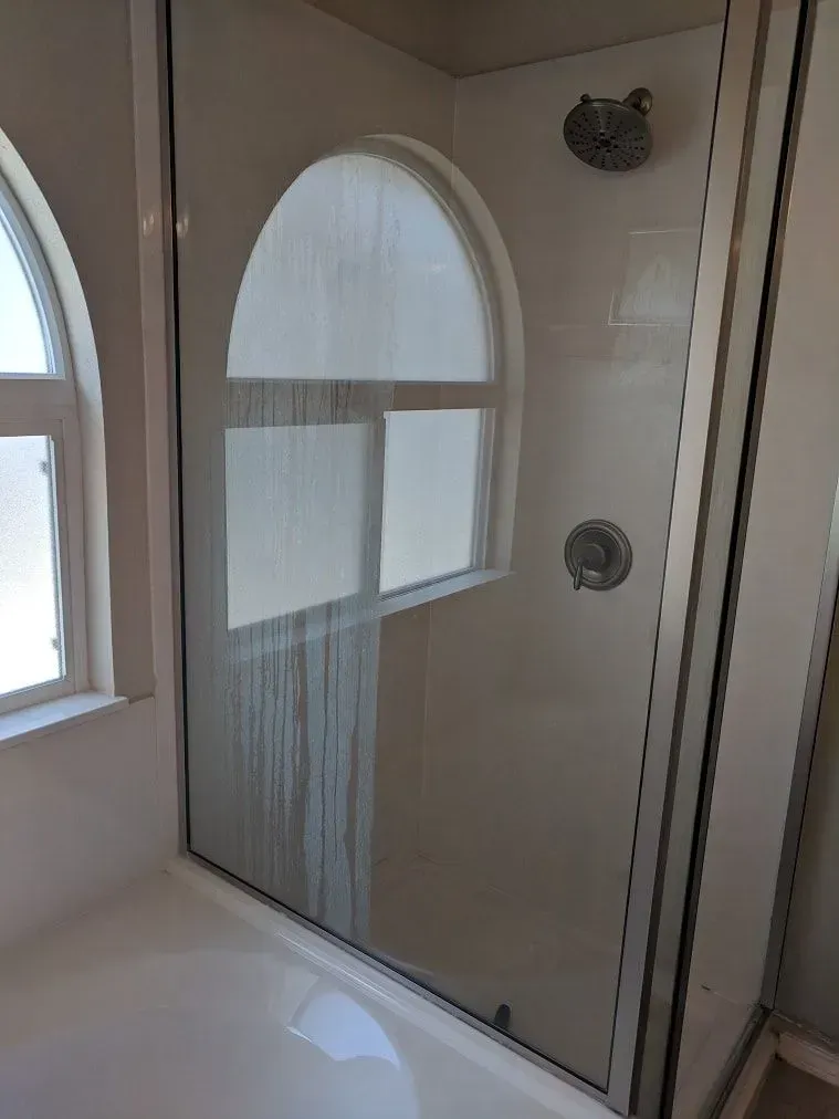A bathroom with a shower and a window.