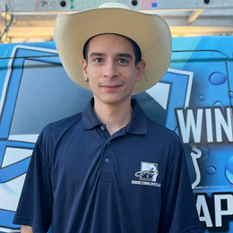 A man wearing a cowboy hat is standing in front of a sign that says win