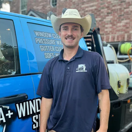 A man wearing a cowboy hat is standing in front of a blue van.