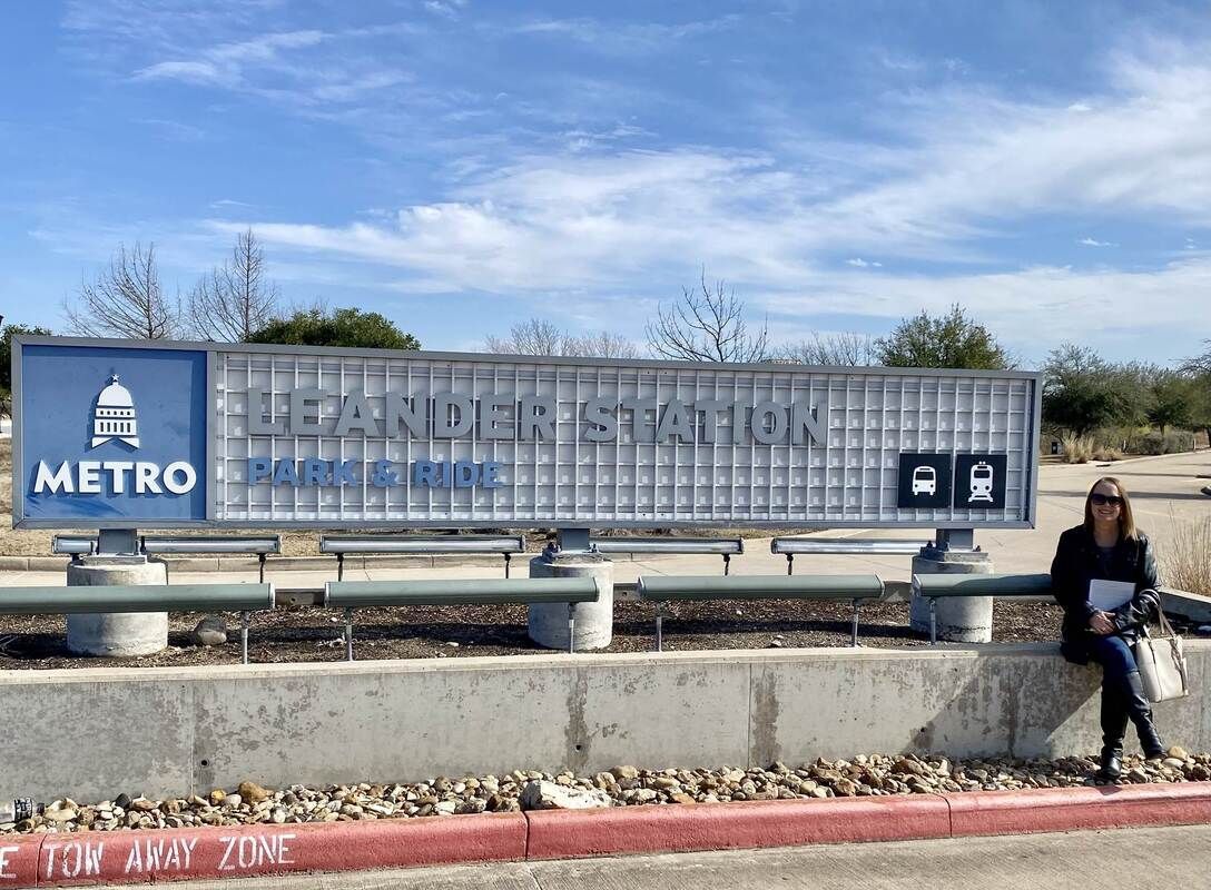 A woman standing next to a Leander Station park & ride metro sign