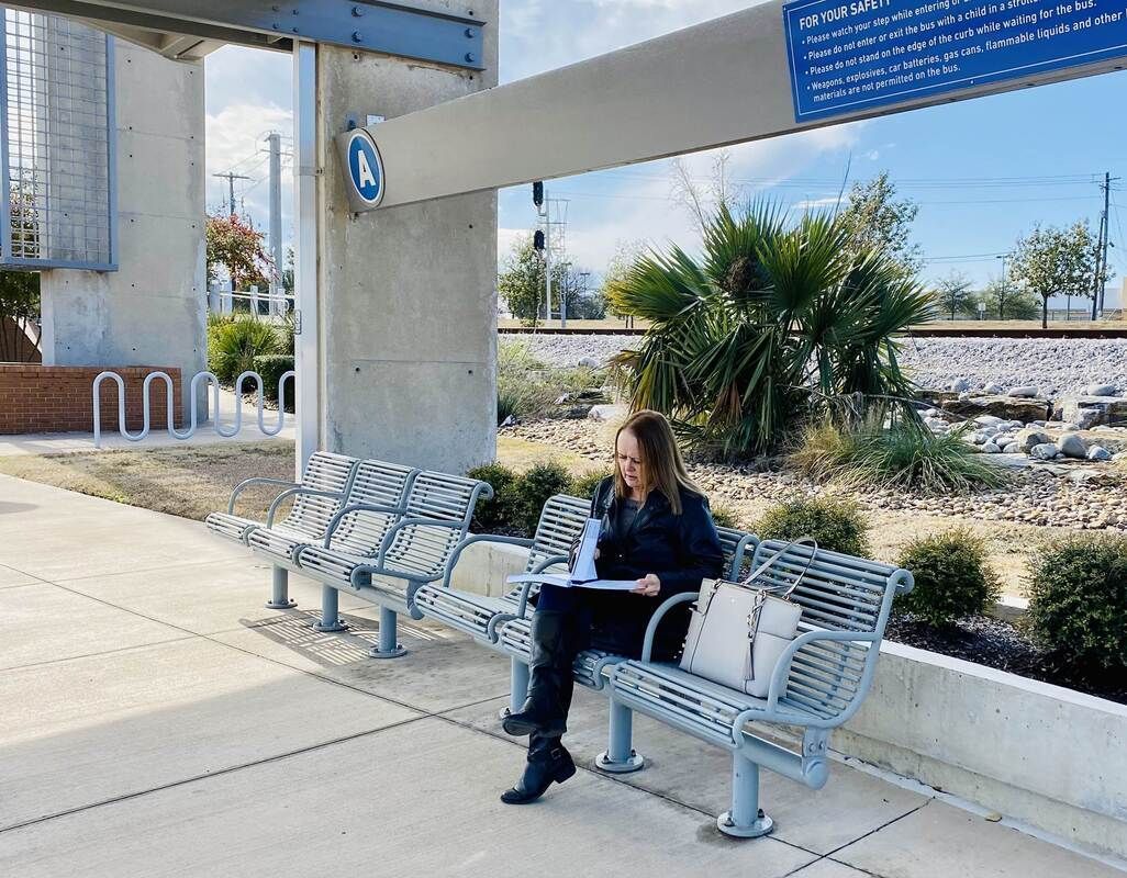 A woman reading whilst sitting at a bus stop.