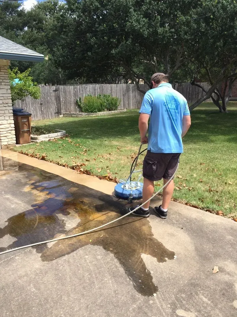 A man is cleaning a driveway with a machine.