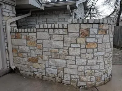A stone wall with a drainpipe on the side of a house.