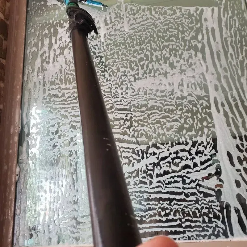 A person is cleaning a window with a vacuum cleaner.