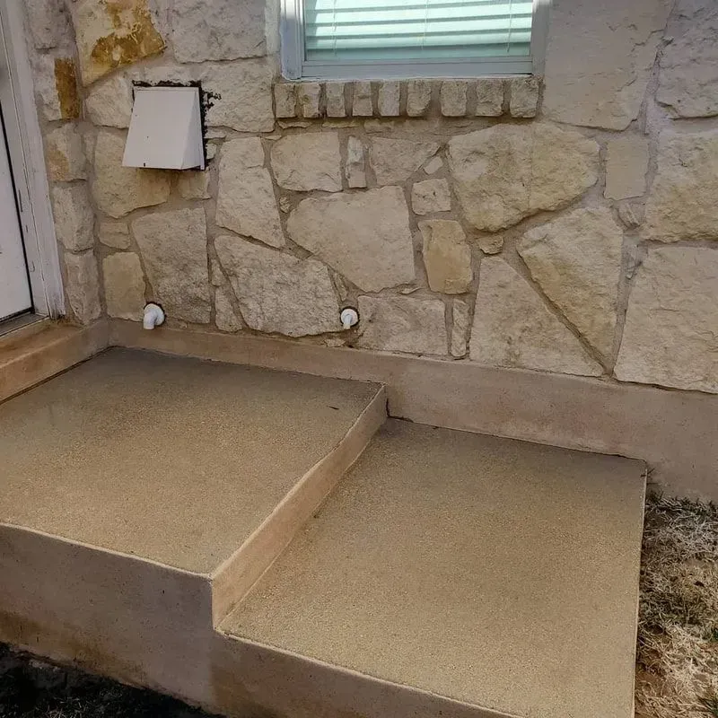 A stone wall with stairs leading up to it and a window.