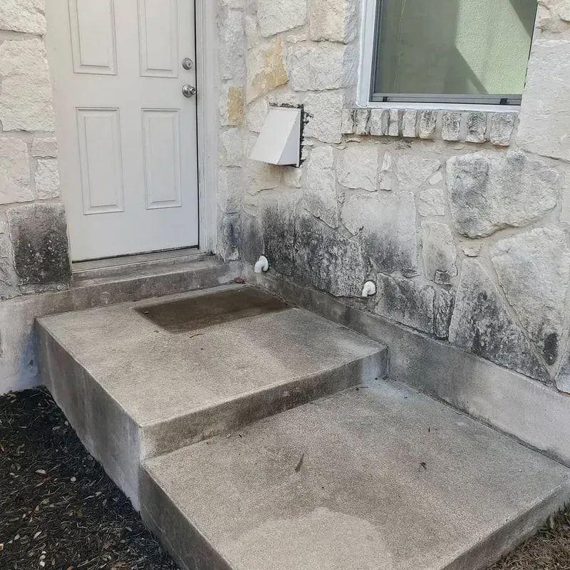 A white door is sitting on a stone wall next to a window.
