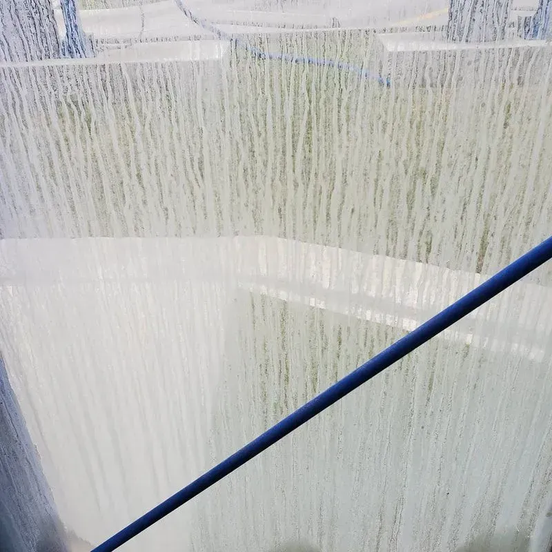 A close up of a window with a blue pole in the foreground